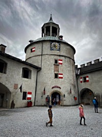 a group of people standing in front of a castle with a clock tower