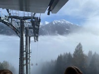 a group of people sitting on a ski lift in the mountains