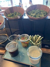 a tray of salads and sauces on a counter