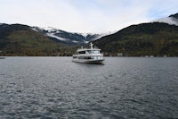 a boat in the middle of a lake with mountains in the background