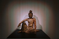 a wooden statue of a buddha sitting on a table