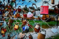 many padlocks are attached to a chain link fence