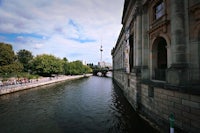 a river next to a building with a tv tower in the background