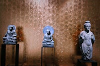 three buddha statues are on display in a room
