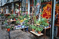 a lot of potted plants on tables in front of a building