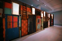 a wall of colorful doors and windows in a museum