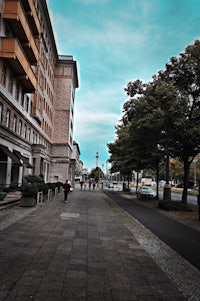 a sidewalk with trees and a building in the background