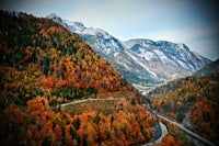 an aerial view of a mountain road in the fall